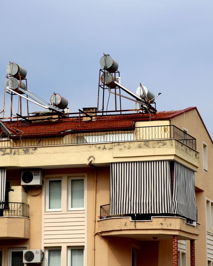 About A close-up view of an urban residential building featuring solar water heaters on the rooftop.