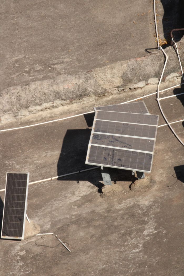 Aerial shot of solar panels on a rooftop in Badami, India under bright sunlight.